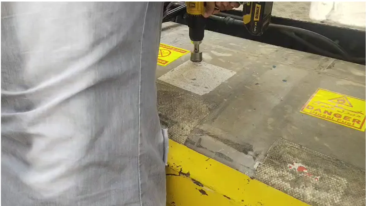 Technician cutting a mounting hole in the top of a diesel tank with a hole saw, DANGER Diesel Fuel warning labels visible